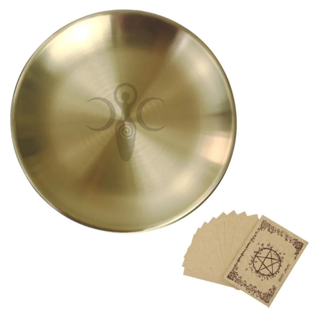 A round, brass-colored stainless steel altar plate with a pentagram design and a small handle, next to several paper cards.
