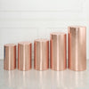 A row of tall, cylindrical rose gold spandex stands displayed against a white wall.