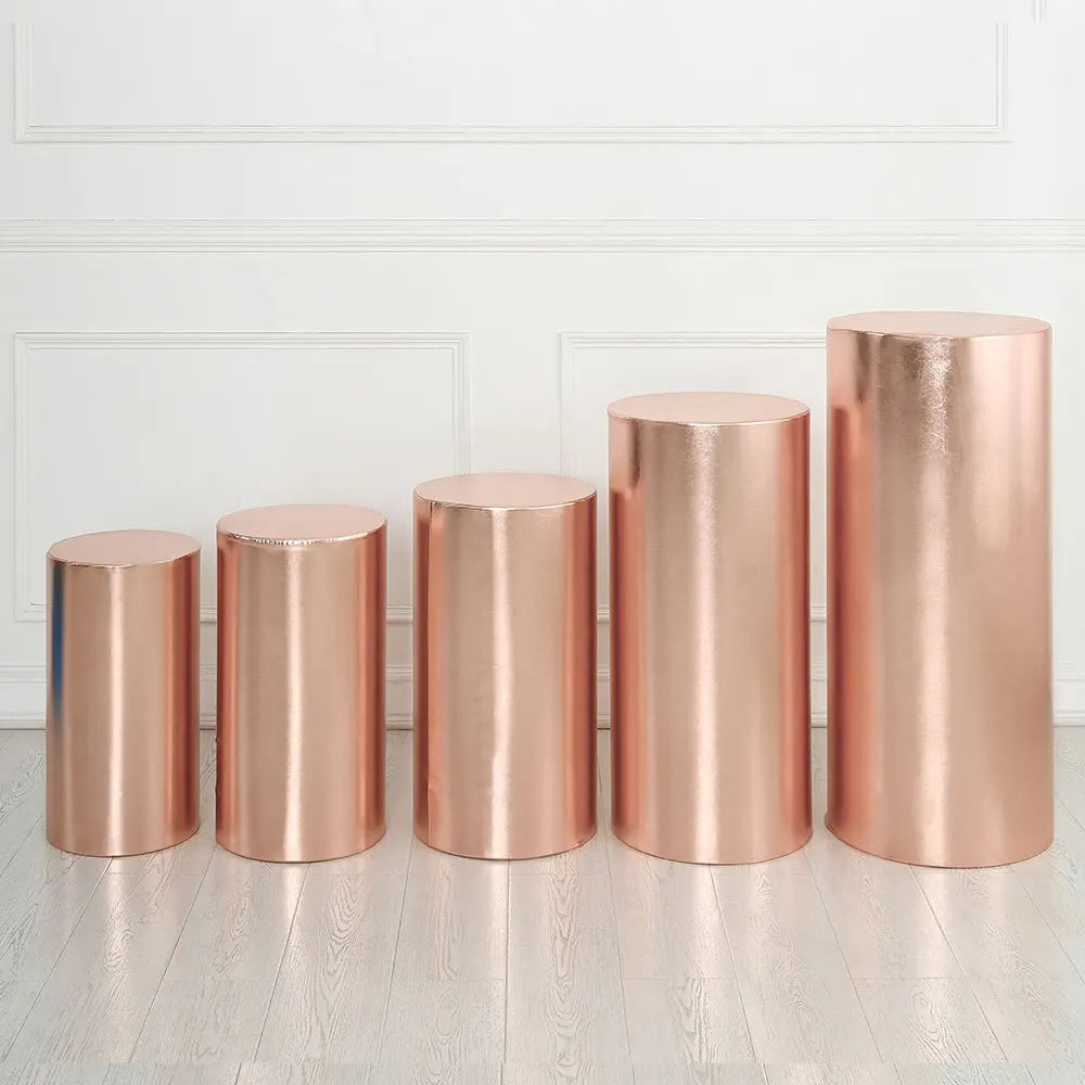 A row of tall, cylindrical rose gold spandex stands displayed against a white wall.