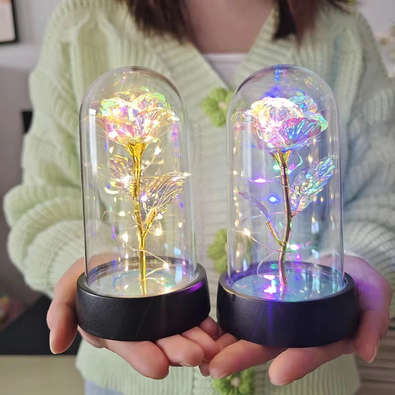 Une main tient une rose de verre éternelle avec une lumière LED pour la décoration intérieure, brillant vivement.