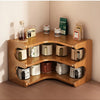 A wooden three-tier corner shelf with bamboo storage for plants and books, displaying various jars and books.