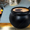 A black cauldron mug with a handle filled with a dark beverage, next to colorful Halloween treats.