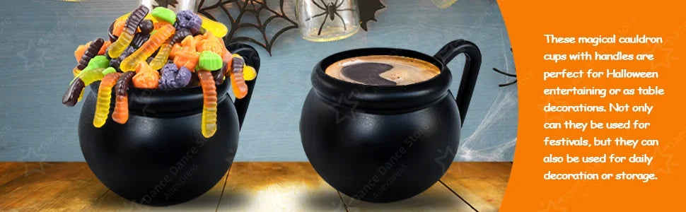 A black cauldron mug with a handle filled with a dark beverage, next to colorful Halloween treats.