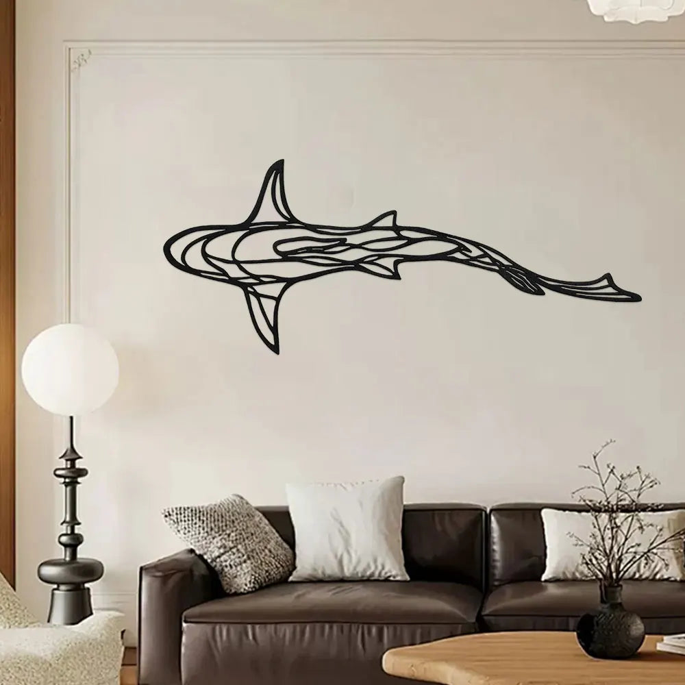 Black metal line sculpture of a shark swimming across a white wall above a dark brown sofa.