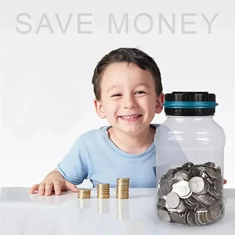 A smiling boy is sitting at a table with coins in front of a clear glass jar and a digital coin counting piggy bank.