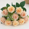 A bouquet of artificial peach and cream roses with green leaves for wedding decoration.