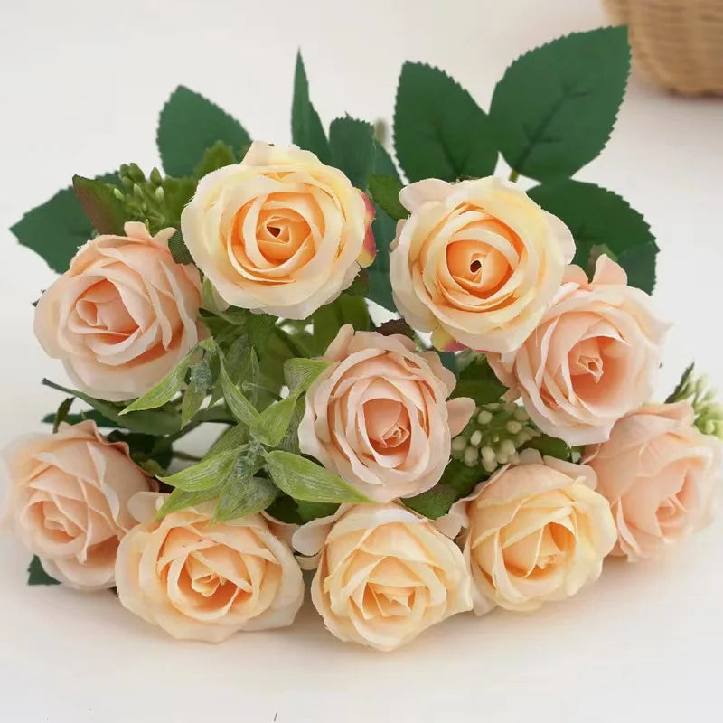 A bouquet of artificial peach and cream roses with green leaves for wedding decoration.