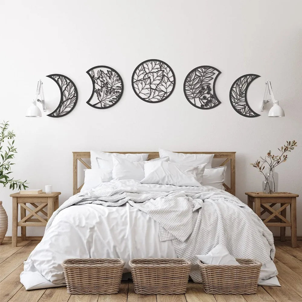 Nordic wooden moon phase wall art featuring various crescent and full moon shapes on a white wall above a bed.