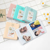 A set of three pink and teal photo albums for instant film, displayed on a white tiled surface.