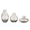 A set of three minimalist glass bud vases with varying shapes and sizes.