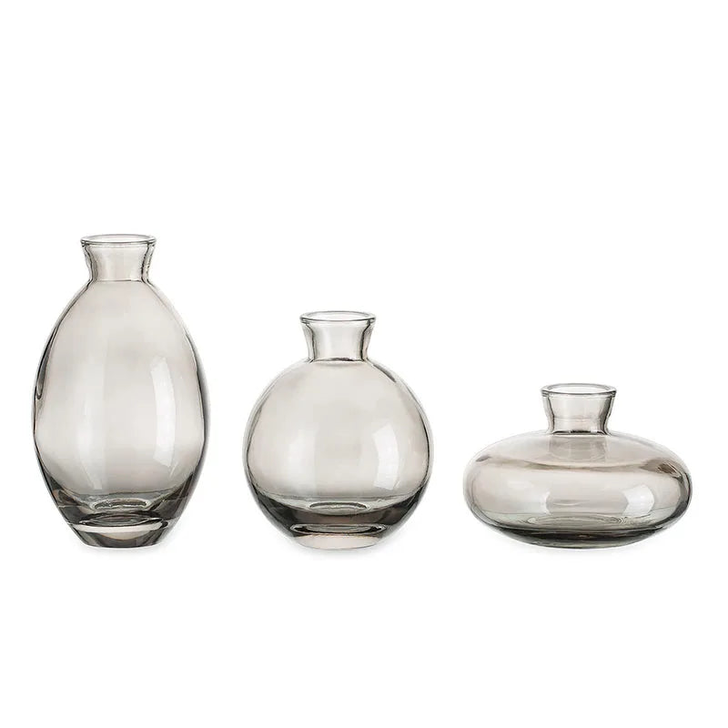 A set of three minimalist glass bud vases with varying shapes and sizes.
