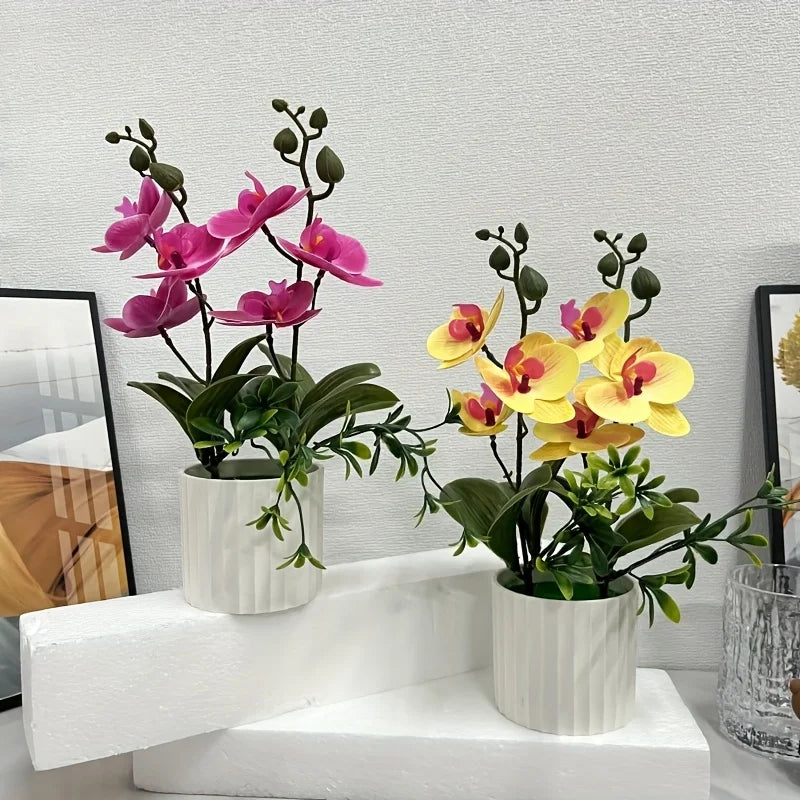 Artificial pink and yellow phalaenopsis orchids in white pots displayed on a white surface.