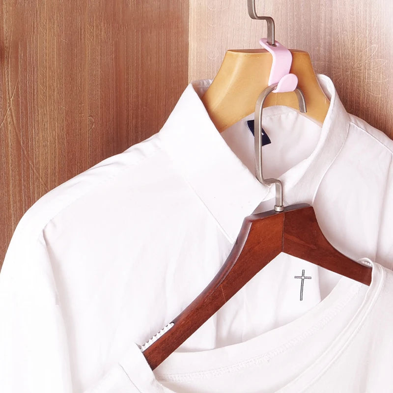 A white shirt is displayed on a wooden hanger with a metal hook connector.