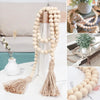 A handmade wood and jute bead garland with a tassel displayed on a white surface.