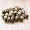 A collection of 20 realistic resin mini skulls used for garden decor, arranged on a light wooden surface.