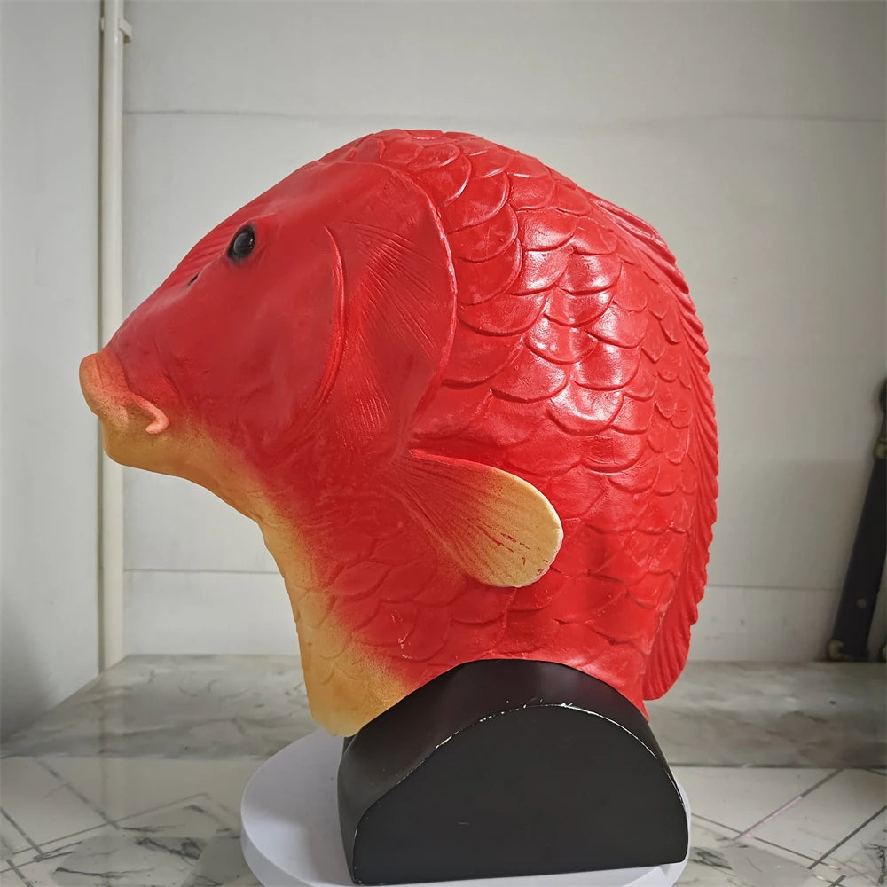 A realistic red fish head latex costume mask with scale texture displayed on a stand.
