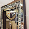 A tall, rectangular silver crystal beveled wall mirror with a dark frame reflecting an interior room.