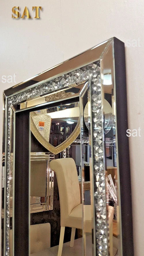 A tall, rectangular silver crystal beveled wall mirror with a dark frame reflecting an interior room.