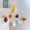 A collection of eight small ceramic vases and glass bottles in various colors like yellow, orange, red, and green displayed o