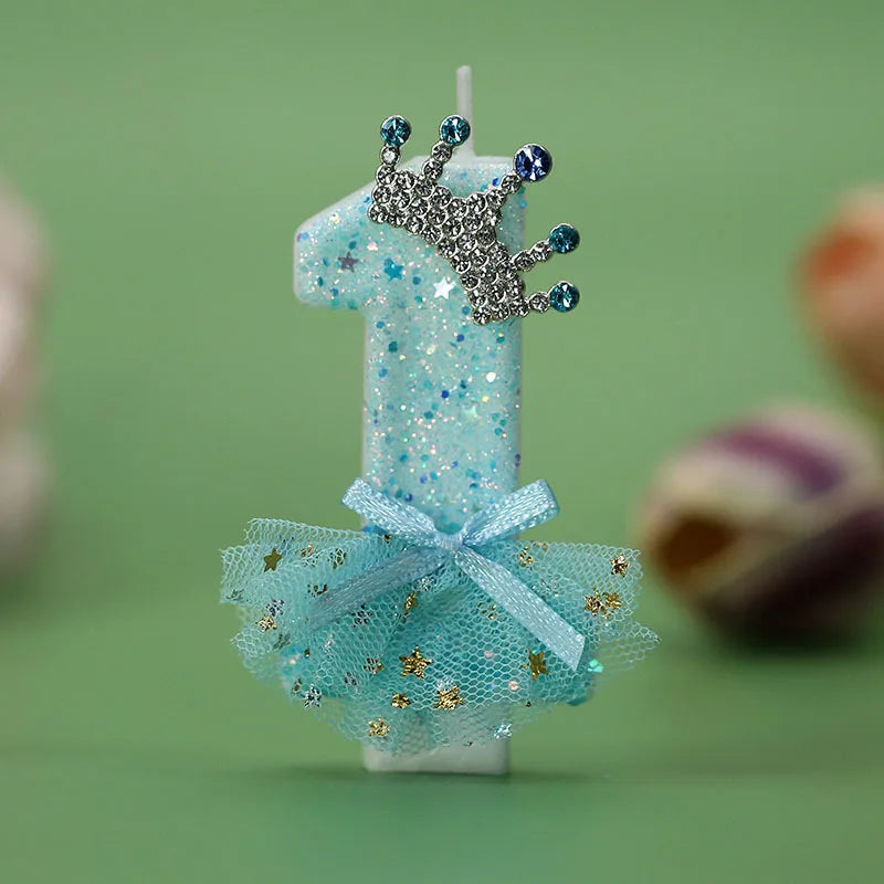 A light blue digital birthday candle decorated with a silver crown topper and a sheer blue tulle skirt.