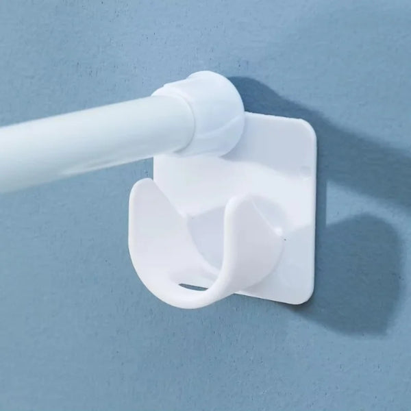 White self-adhesive curtain rod brackets with adjustable clips mounted on a light blue wall.