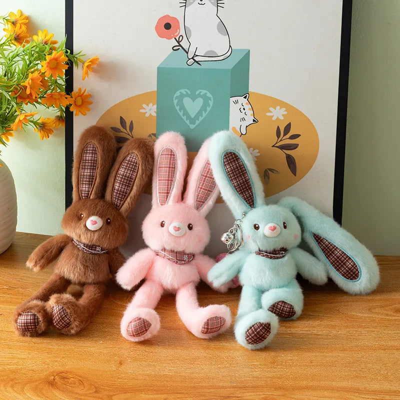 Three giant kawaii rabbit plush toys in brown pink and light blue sitting on a wooden surface.
