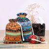 A set of vintage cotton drawstring gift pouches in various earthy and colorful patterns resting on a wooden surface.