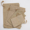A stack of natural burlap drawstring bags in beige color.