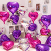 A collection of iridescent foil heart balloons in shades of purple and pink displayed on a white shelf.