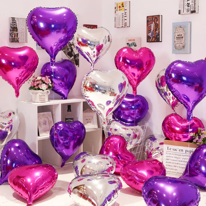 A collection of iridescent foil heart balloons in shades of purple and pink displayed on a white shelf.