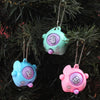 Three pastel colored guessing game eggs in various shades of blue and pink hanging on a dark green pine branch