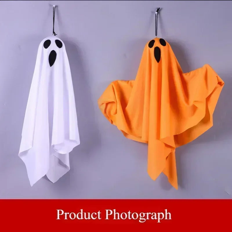 An orange fabric ghost decoration hanging on a gray wall.