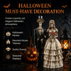 A dark Halloween decoration featuring a gothic skeleton couple statue with a suit and a lace dress, alongside a carved pumpki