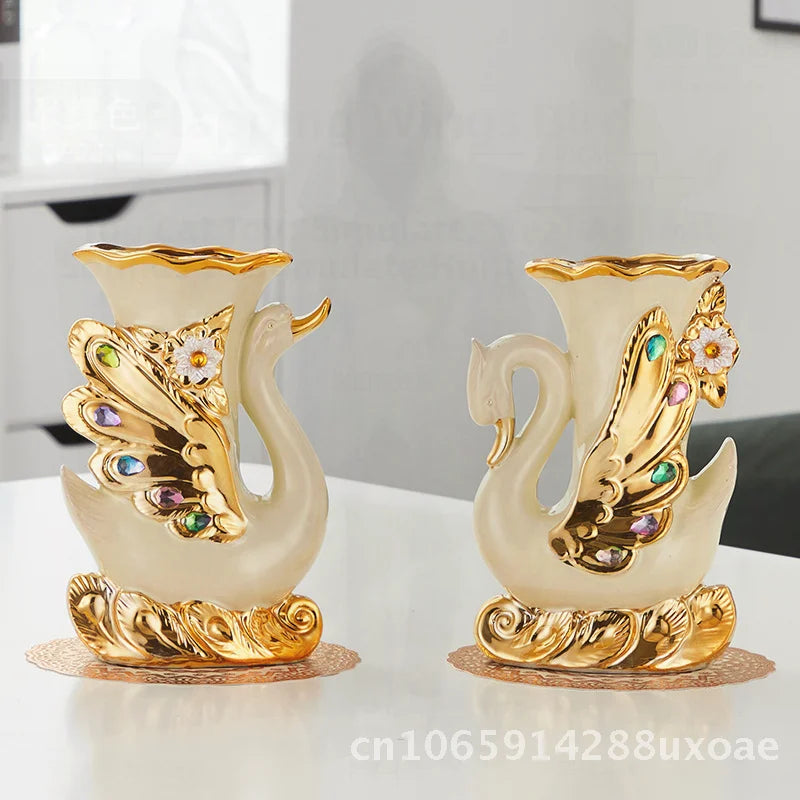 A pair of elegant ceramic swan vases featuring cream and gold finishes for modern home decor.