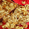 A pile of gold silk rose petals scattered on a red fabric surface.