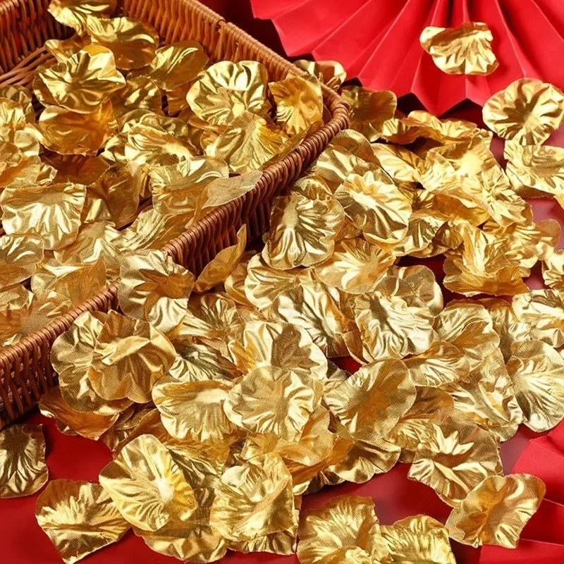 A pile of gold silk rose petals scattered on a red fabric surface.