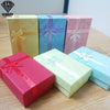 Colección de cajas de regalo decorativas de joyería coloridas en tonos amarillo, azul, rosa y rojo apiladas sobre una madera