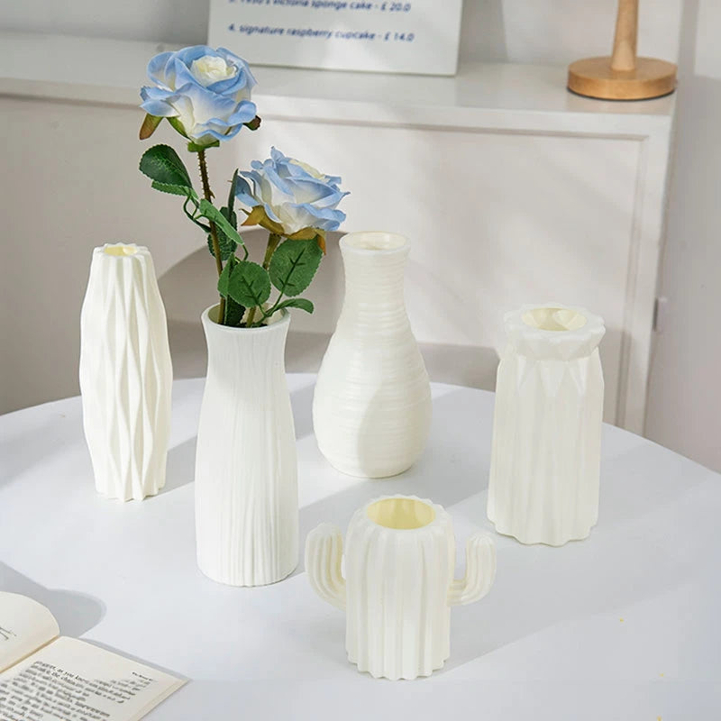 Eine weiße moderne Plastikblumenvase hält eine blaue Rose und grüne Blätter auf einem weißen Tisch.
