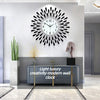 A modern minimalist metal wall clock with a spiky design mounted on a white wall.