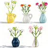 A collection of five ceramic vases holding colorful flowers in yellow, white, and blue tones.