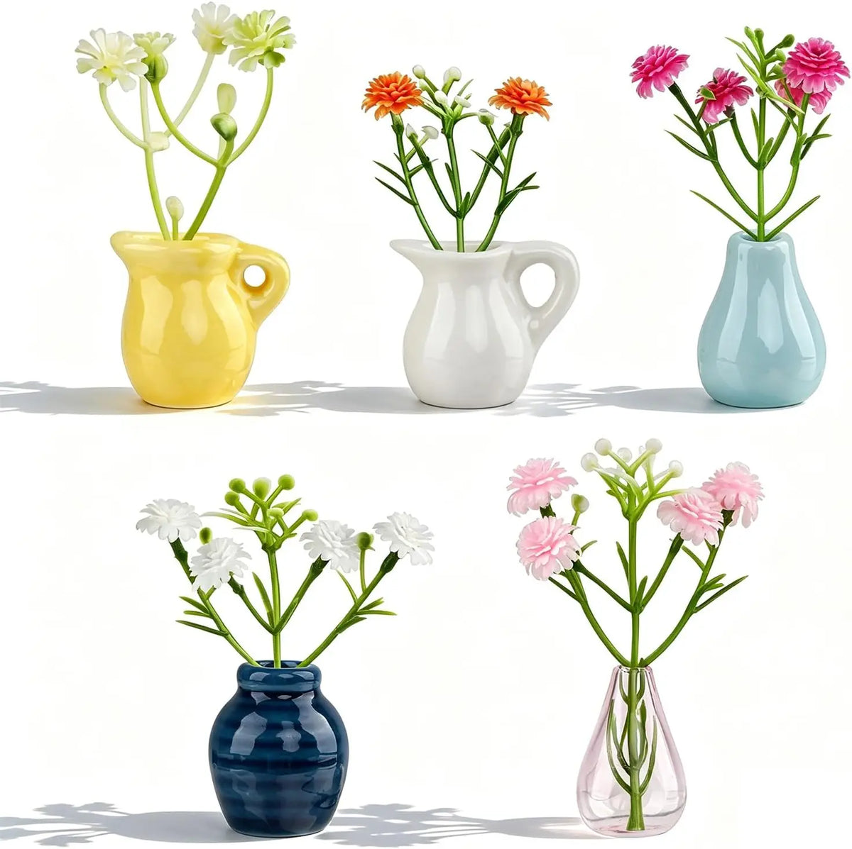 A collection of five ceramic vases in yellow, white, and blue holding small flowers.