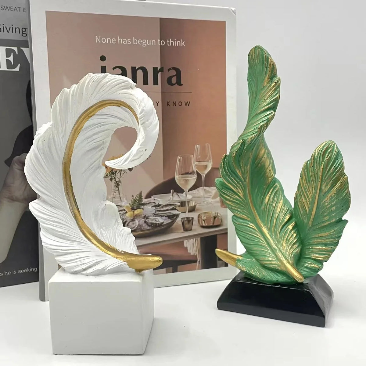 A white and gold artistic feather sculpture centerpiece displayed next to a box featuring the brand Ianra.