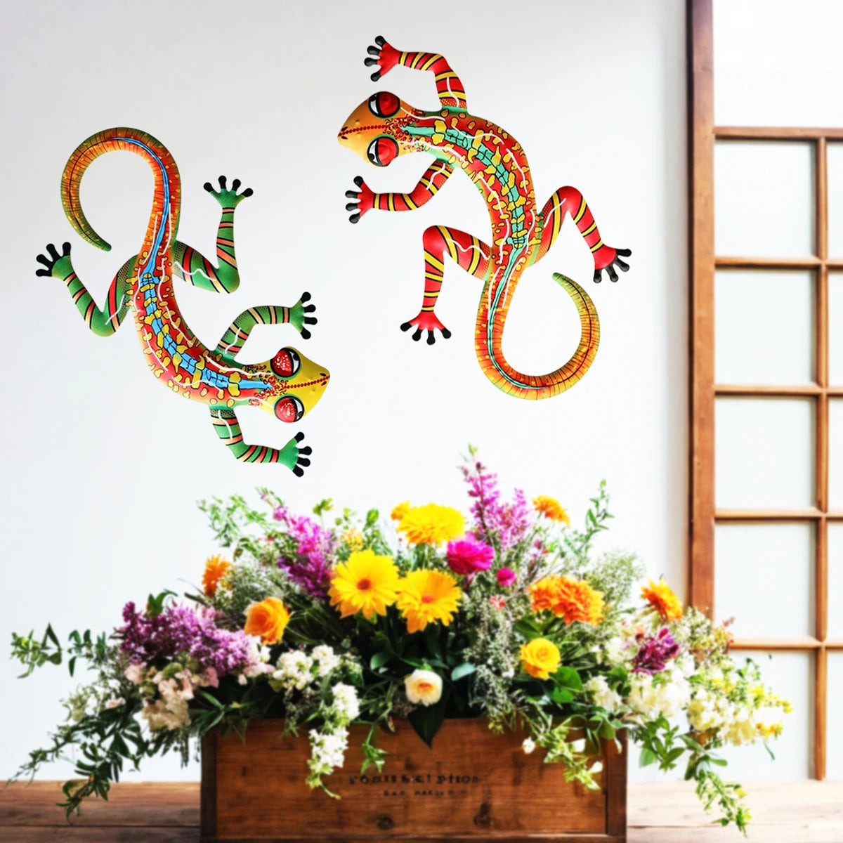 Handcrafted metal gecko wall art featuring colorful lizard figures displayed above a floral arrangement.