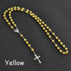 A yellow bead rosary necklace featuring a silver cross and a small pendant.