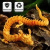 A bright orange color-changing flexible dragon figurine resting on dark brown rocks.