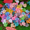 A collection of miniature resin flamingo duck figurines in various pastel colors scattered on green moss.