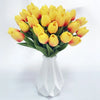 A bouquet of artificial yellow and orange tulips in a white vase for home decor.