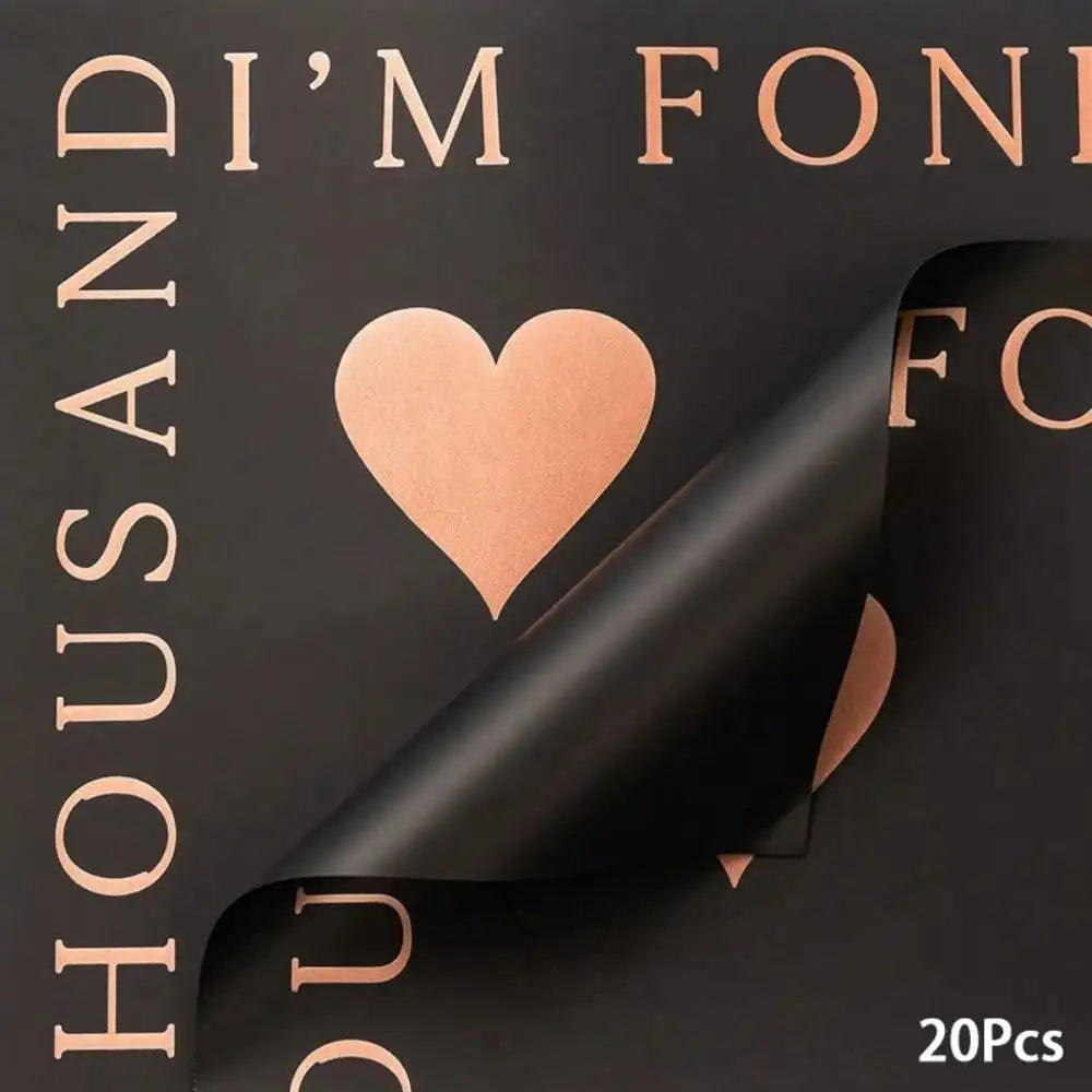 A close-up of a dark brown wrapping paper featuring gold lettering and a heart design.
