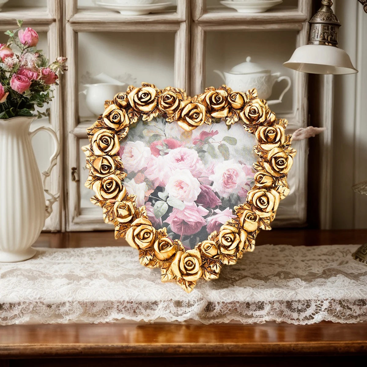 A heart-shaped frame made of gold-colored roses surrounds a floral resin photo, displayed on a wooden surface.