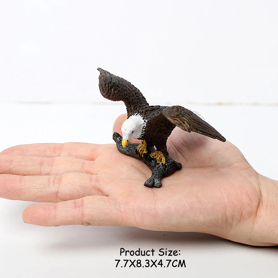 A realistic figurine set of an owl, vulture, and bald eagle perched on a human hand.